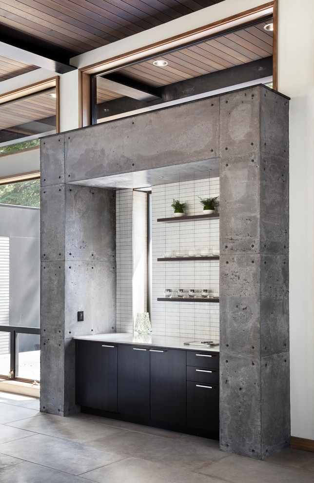 Modelo de bar en casa lineal urbano con armarios con paneles lisos, puertas de armario negras, salpicadero blanco, suelo de cemento y suelo gris