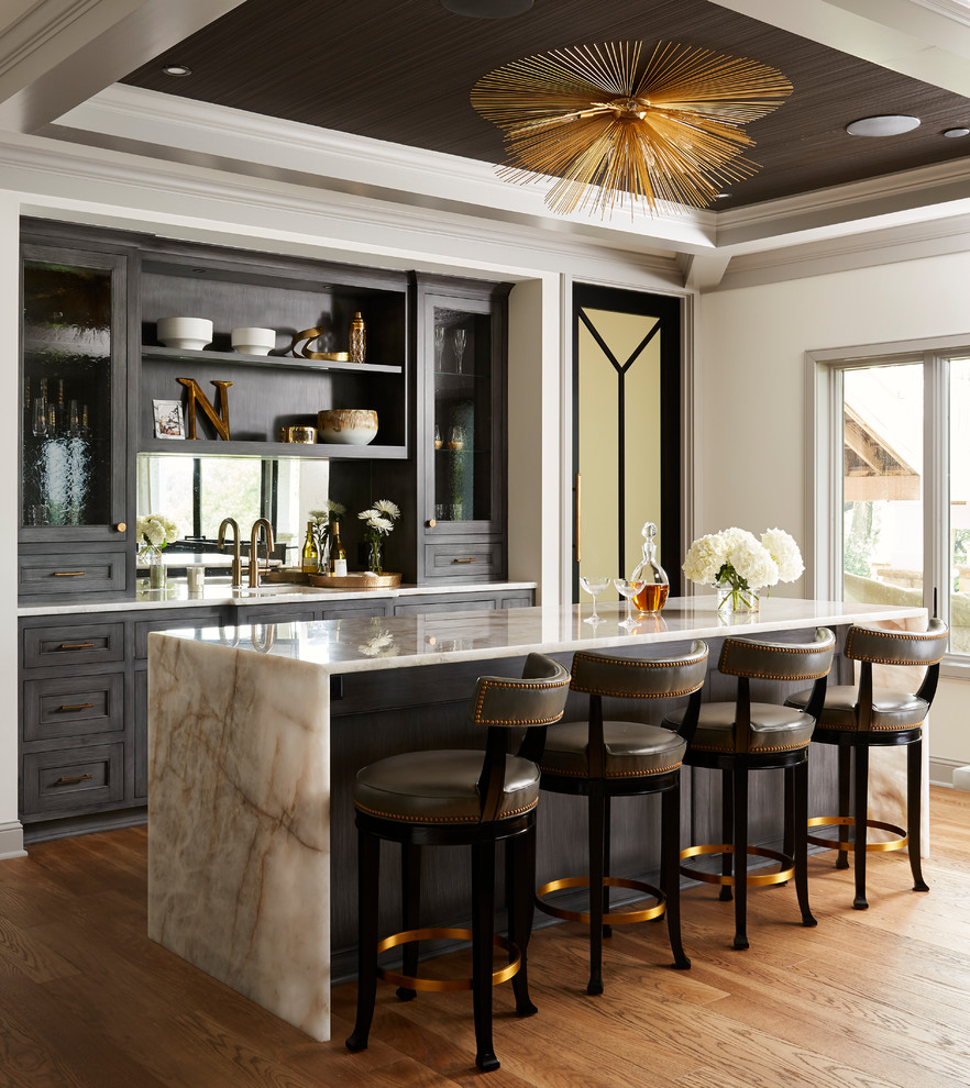 Inspiration for an expansive classic galley wet bar in Minneapolis with a submerged sink, recessed-panel cabinets, dark wood cabinets, quartz worktops, mirror splashback, medium hardwood flooring, brown floors and white worktops.