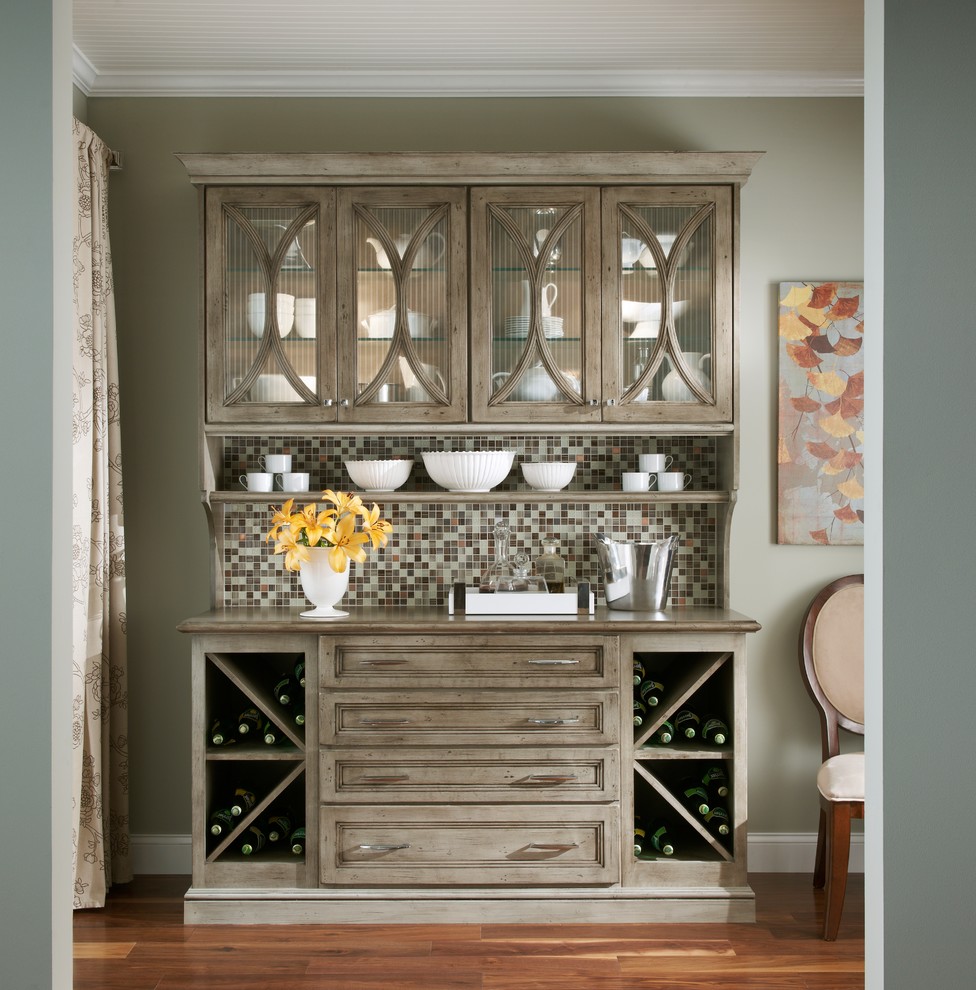 This is an example of a small traditional single-wall home bar in Minneapolis with glass-front cabinets, distressed cabinets, granite worktops, multi-coloured splashback, mosaic tiled splashback, dark hardwood flooring and brown floors.