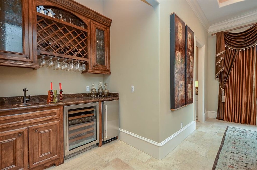 Photo of a large mediterranean single-wall wet bar in Houston with a built-in sink, glass-front cabinets, medium wood cabinets, brown splashback, marble splashback, ceramic flooring, beige floors and brown worktops.