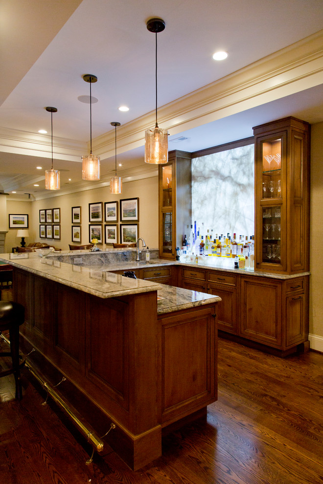 Large transitional u-shaped medium tone wood floor and brown floor seated home bar photo in St Louis with an undermount sink, glass-front cabinets, medium tone wood cabinets, granite countertops and stone slab backsplash
