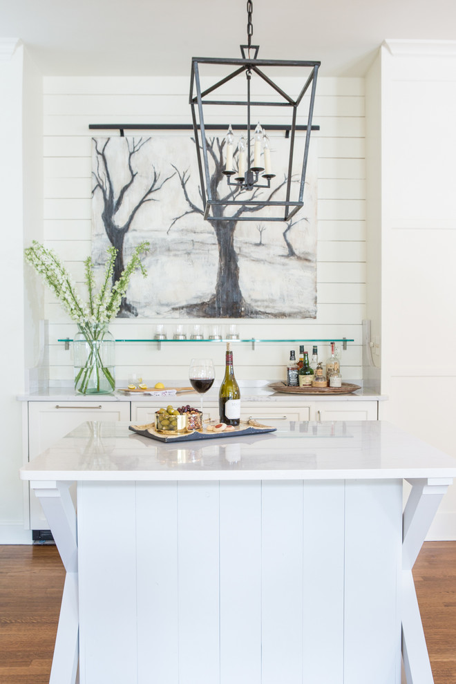 Example of a transitional medium tone wood floor home bar design in Other with no sink, shaker cabinets, white cabinets, white backsplash, wood backsplash and white countertops