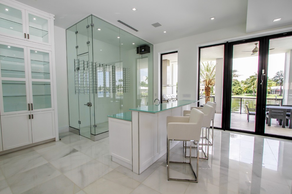 Example of a large minimalist l-shaped marble floor and white floor home bar design in Miami with an undermount sink, shaker cabinets, white cabinets, quartz countertops, gray backsplash and glass tile backsplash