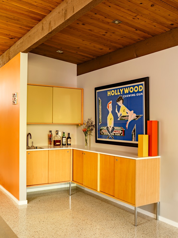 Inspiration for a mid-sized 1960s l-shaped beige floor and concrete floor wet bar remodel in Portland with flat-panel cabinets, light wood cabinets, an undermount sink and white countertops