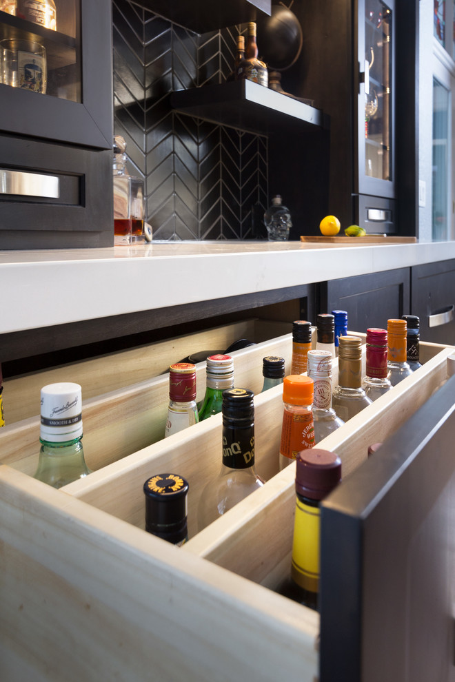 Small contemporary galley wet bar in Other with a submerged sink, recessed-panel cabinets, black cabinets, engineered stone countertops, black splashback, ceramic splashback, porcelain flooring, brown floors and white worktops.