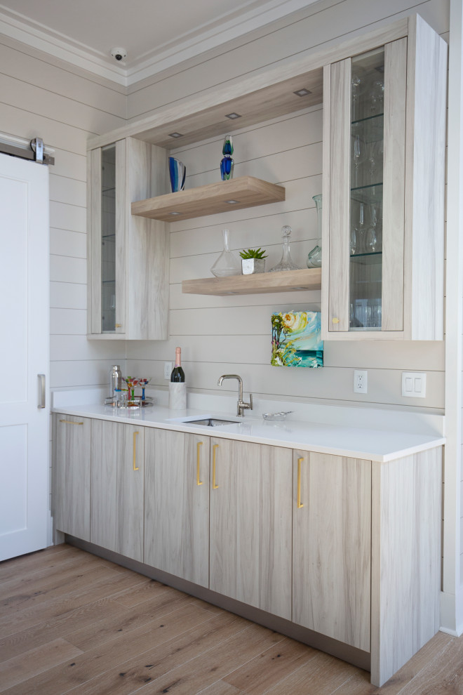 Design ideas for a medium sized beach style single-wall wet bar in Miami with a built-in sink, flat-panel cabinets, light wood cabinets, quartz worktops, white splashback, light hardwood flooring, beige floors and white worktops.