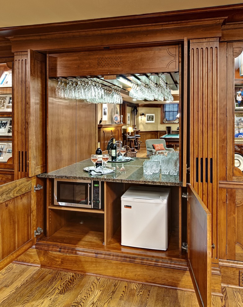 Medium sized classic single-wall home bar in Minneapolis with medium wood cabinets, granite worktops, mirror splashback, medium hardwood flooring and brown floors.