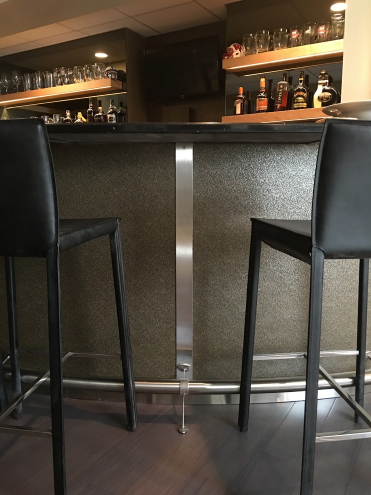Example of a large minimalist u-shaped dark wood floor and brown floor seated home bar design in Philadelphia with shaker cabinets, light wood cabinets, solid surface countertops, black backsplash and black countertops