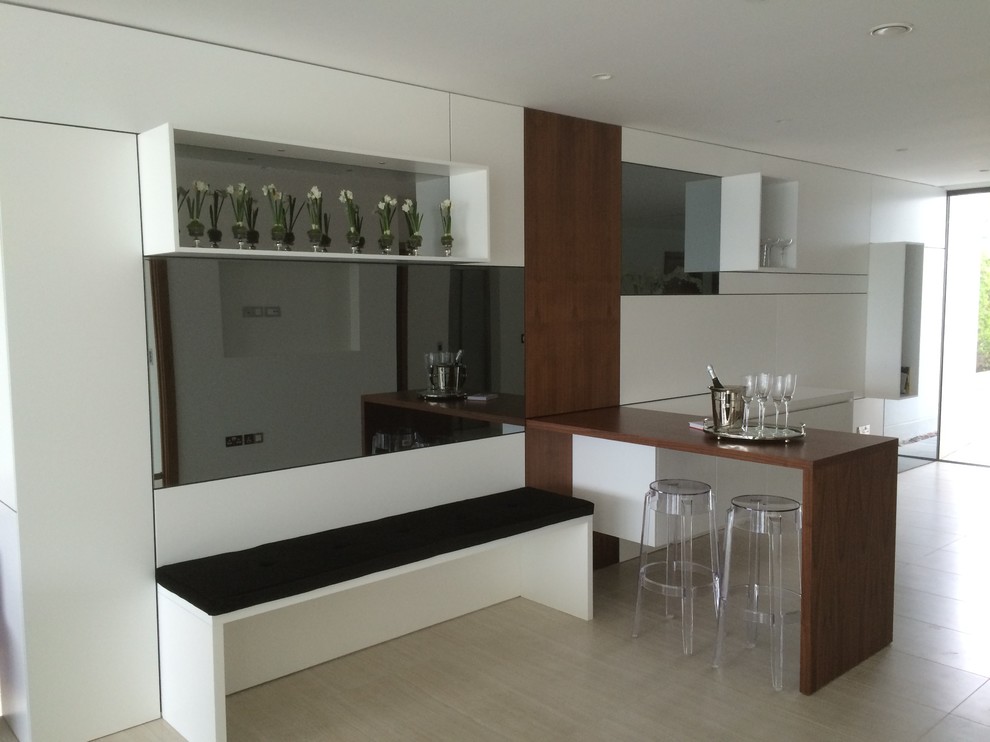 This is an example of a medium sized contemporary single-wall wet bar in Dorset with flat-panel cabinets, white cabinets, wood worktops, white splashback, glass sheet splashback and ceramic flooring.