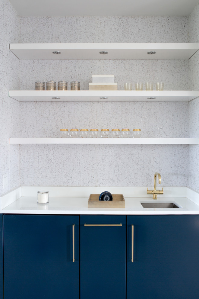 Cette image montre un petit bar de salon avec évier linéaire minimaliste avec un évier encastré, un placard à porte plane, des portes de placard bleues et un plan de travail blanc.