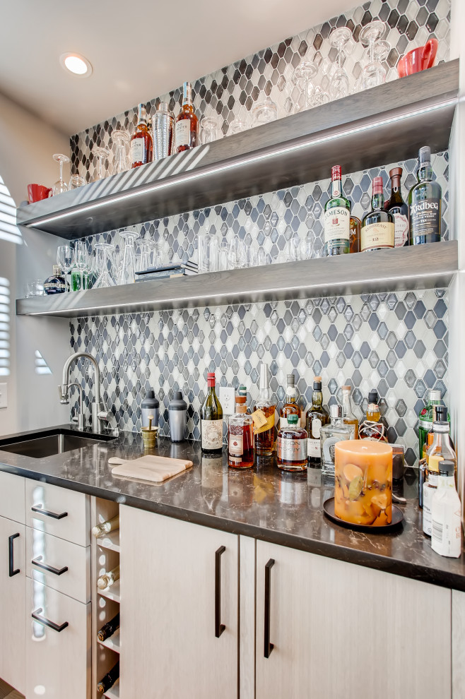 This is an example of a contemporary wet bar in Denver with a submerged sink, flat-panel cabinets, beige cabinets, multi-coloured splashback, black worktops and a feature wall.