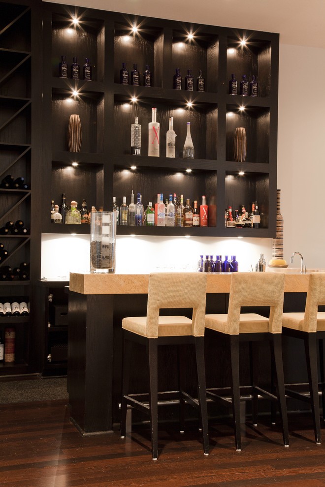 Immagine di un bancone bar minimal di medie dimensioni con nessun'anta, ante in legno bruno, paraspruzzi bianco e parquet scuro