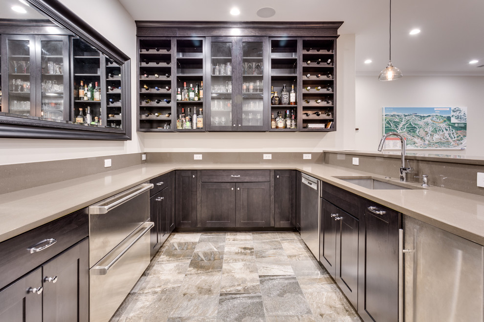 This is an example of a traditional u-shaped wet bar in DC Metro with a submerged sink, shaker cabinets, dark wood cabinets and grey floors.