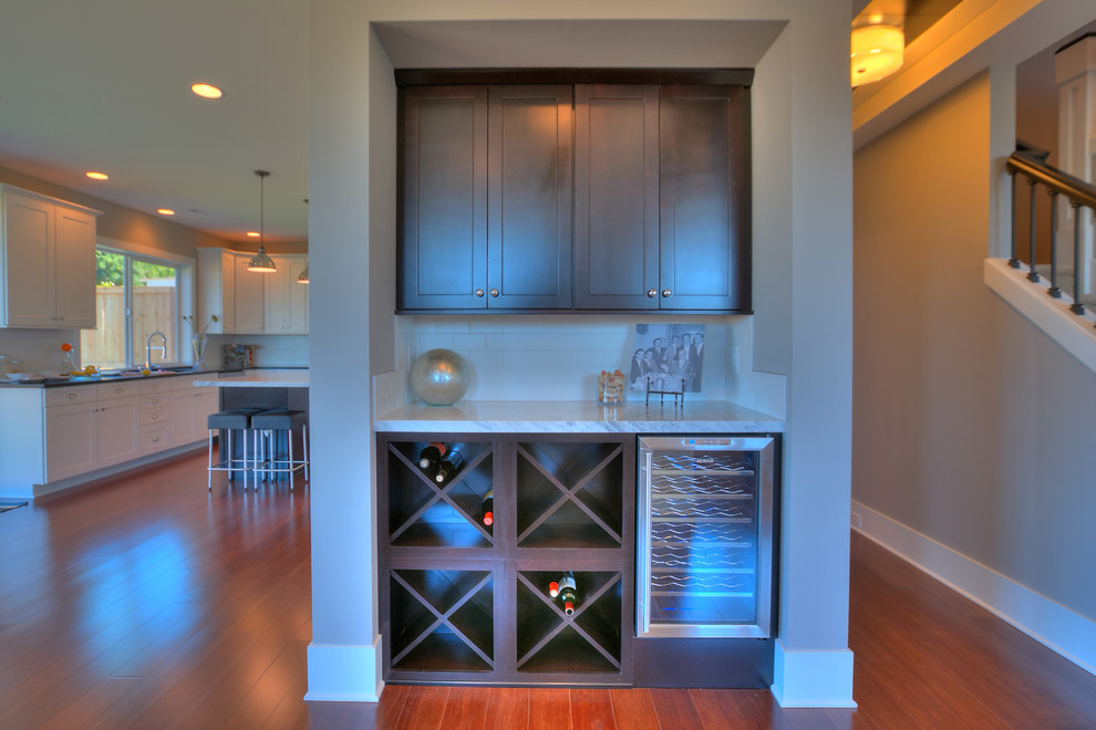 Example of a small transitional galley bamboo floor and brown floor home bar design in Seattle with flat-panel cabinets, dark wood cabinets, solid surface countertops, white backsplash and ceramic backsplash