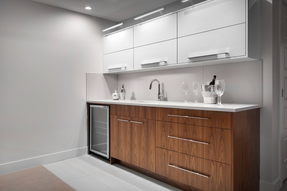 Photo of a small contemporary single-wall wet bar in Calgary with a submerged sink, flat-panel cabinets, medium wood cabinets, engineered stone countertops, grey splashback, ceramic splashback and ceramic flooring.