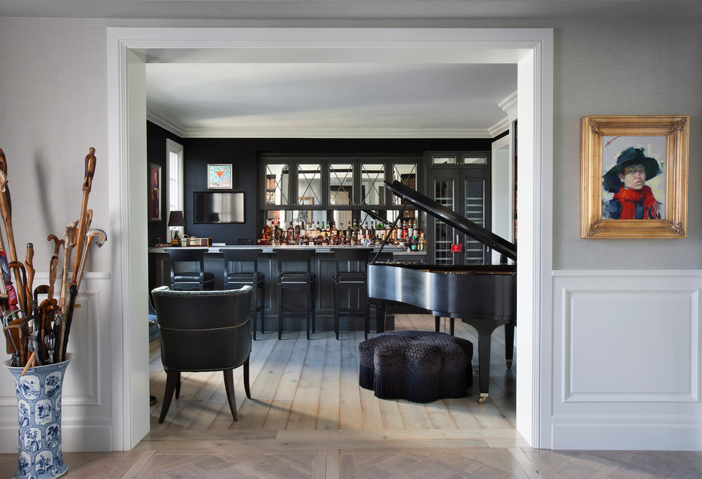 Modelo de bar en casa con barra de bar tradicional renovado con puertas de armario negras, salpicadero con efecto espejo, suelo de madera clara y suelo beige