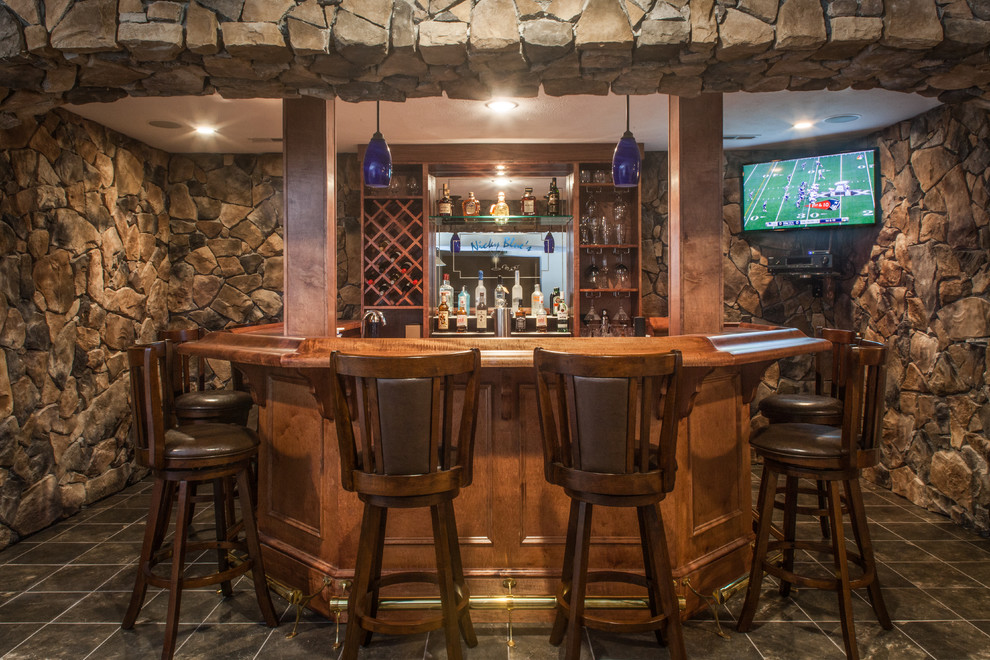 Large mountain style u-shaped porcelain tile and gray floor seated home bar photo in Other with an undermount sink, raised-panel cabinets, medium tone wood cabinets, wood countertops, brown backsplash and stone tile backsplash