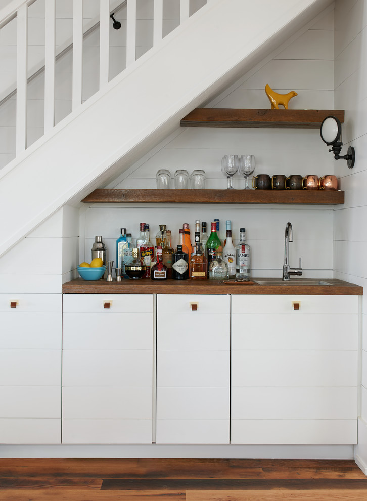 Inspiration for a small coastal single-wall medium tone wood floor and brown floor wet bar remodel in Toronto with wood countertops, white backsplash, brown countertops, flat-panel cabinets and white cabinets