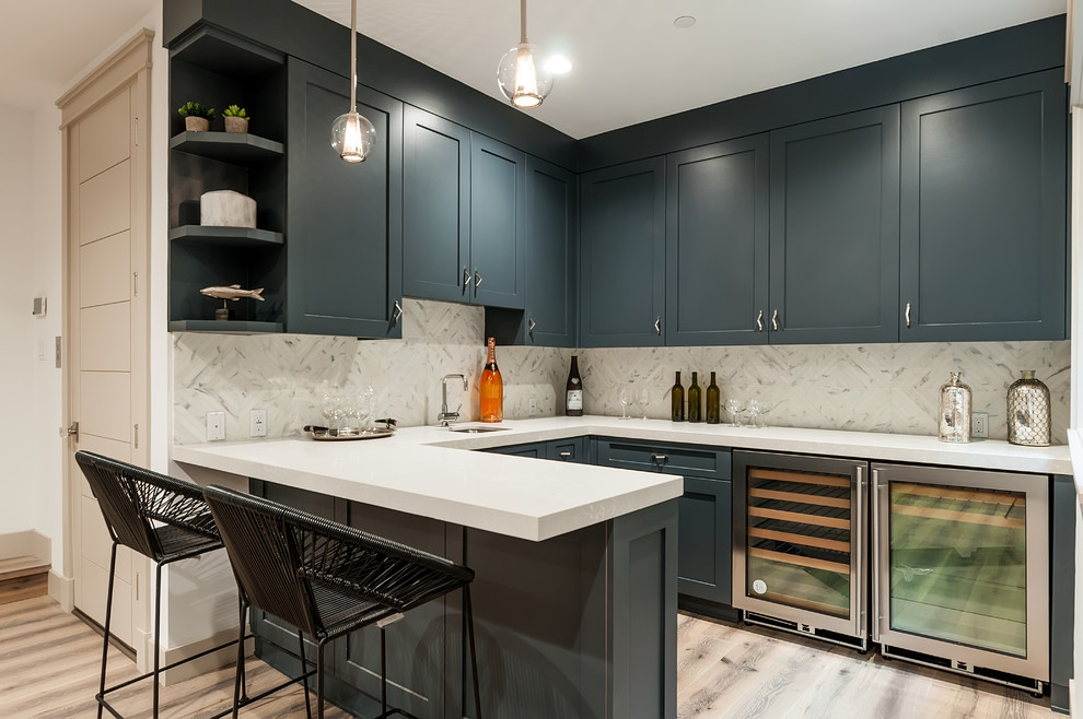 Example of a mid-sized cottage u-shaped light wood floor and brown floor seated home bar design in Los Angeles with an undermount sink, shaker cabinets, blue cabinets, quartz countertops, gray backsplash and marble backsplash