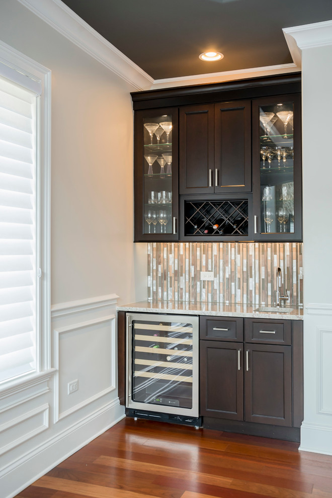 Example of a small minimalist single-wall medium tone wood floor wet bar design in Chicago with an undermount sink, shaker cabinets, dark wood cabinets, granite countertops, multicolored backsplash and mosaic tile backsplash