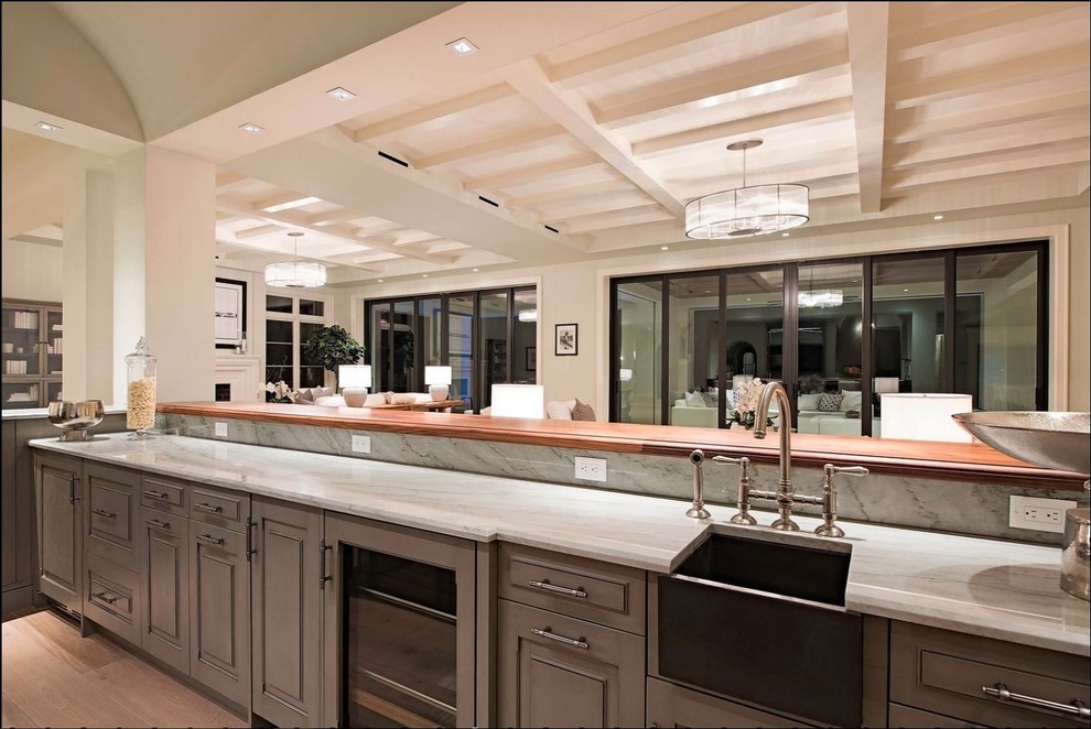 Example of a huge tuscan medium tone wood floor and brown floor wet bar design in Miami with an undermount sink, raised-panel cabinets, gray cabinets, wood countertops, brown backsplash and ceramic backsplash