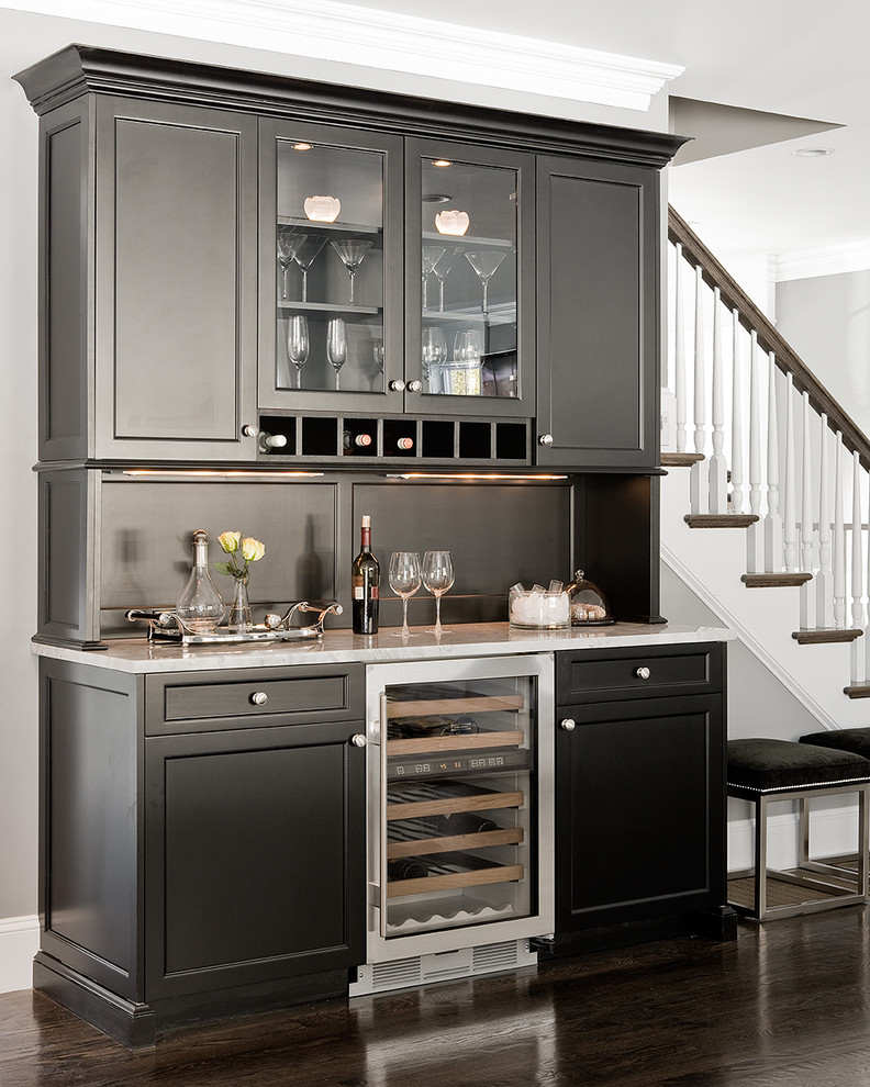 Photo of a traditional home bar in Boston with glass-front cabinets, black cabinets, granite worktops, brown floors and white worktops.