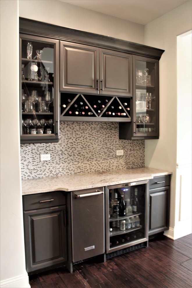 Inspiration for a small timeless single-wall dark wood floor and brown floor home bar remodel in Chicago with no sink, raised-panel cabinets, gray cabinets, granite countertops, glass tile backsplash and white backsplash