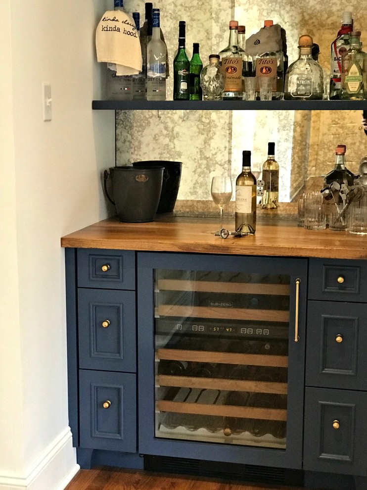 Modelo de bar en casa con fregadero lineal tradicional renovado pequeño sin pila con armarios con rebordes decorativos, puertas de armario azules, encimera de madera, salpicadero con efecto espejo, suelo de madera en tonos medios, suelo marrón y encimeras marrones