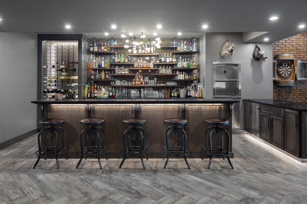 Large urban galley medium tone wood floor and gray floor seated home bar photo in Other with granite countertops, glass tile backsplash, shaker cabinets, dark wood cabinets and black countertops