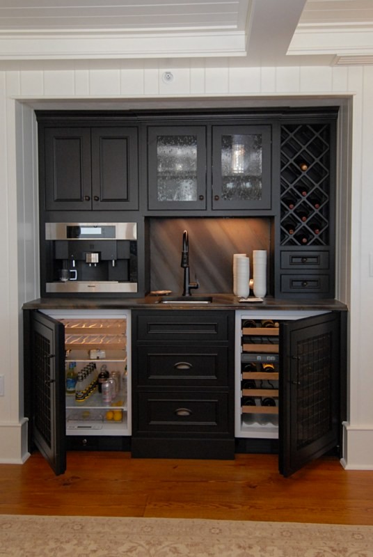 This is an example of a small classic single-wall wet bar in Orlando with a submerged sink, recessed-panel cabinets, black cabinets, laminate countertops, multi-coloured splashback and medium hardwood flooring.