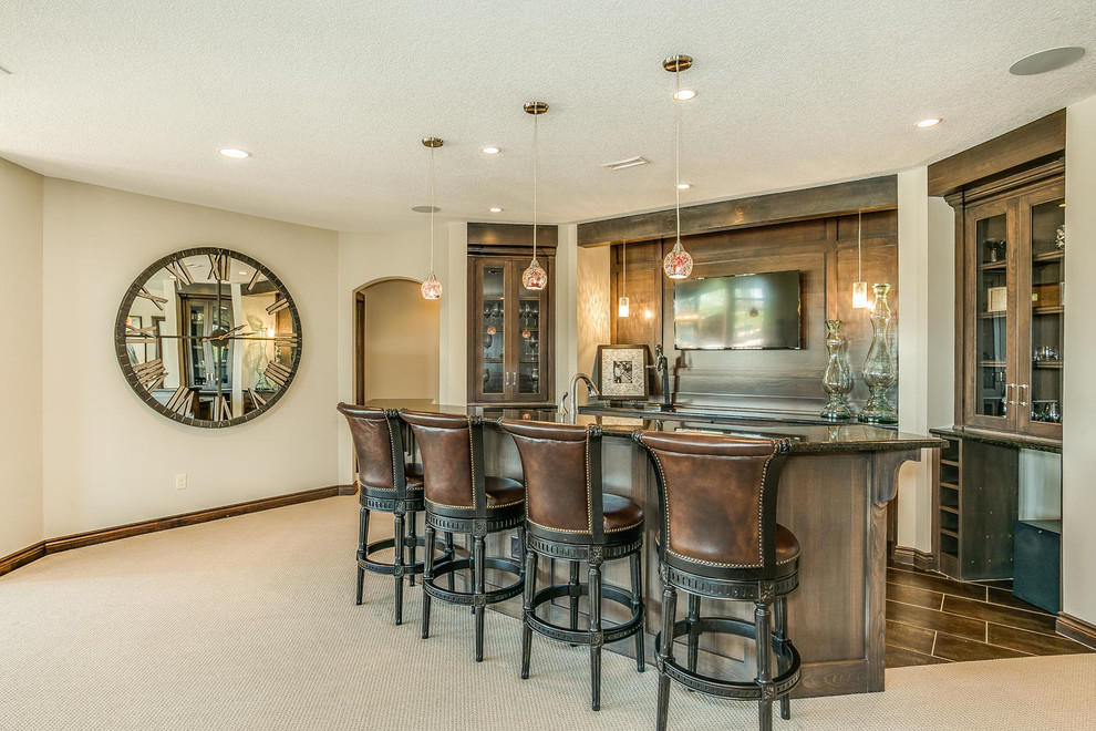 Photo of a medium sized traditional galley breakfast bar in Wichita with glass-front cabinets, dark wood cabinets, carpet and a submerged sink.