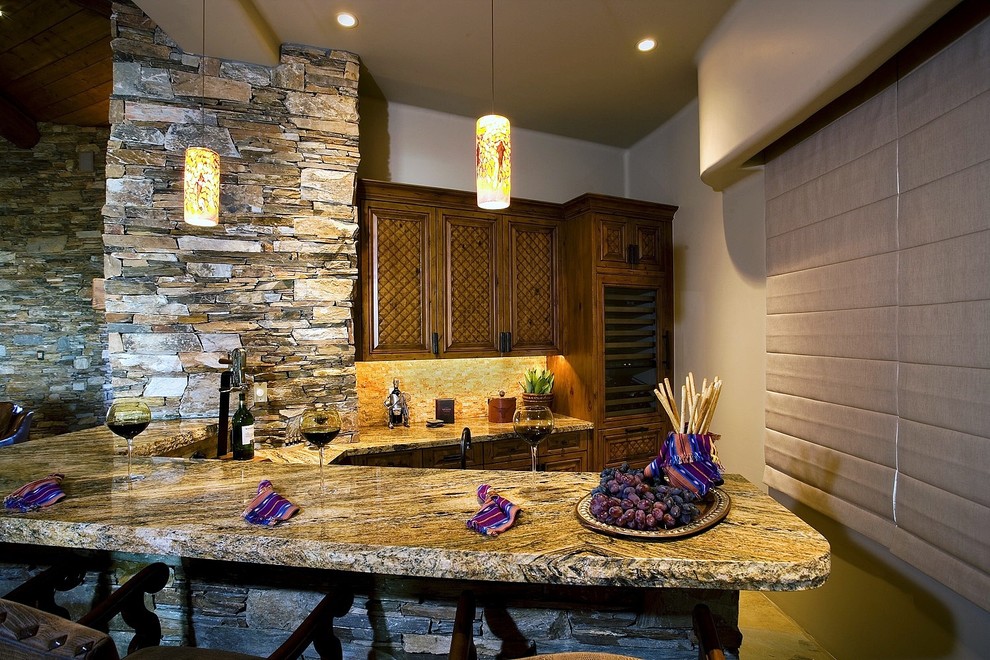 Mid-sized southwest l-shaped seated home bar photo in Phoenix with raised-panel cabinets, medium tone wood cabinets, granite countertops, beige backsplash and travertine backsplash