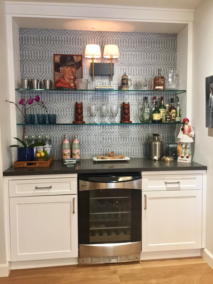 Photo of a small midcentury single-wall home bar in Phoenix with white cabinets, engineered stone countertops, multi-coloured splashback, light hardwood flooring and shaker cabinets.