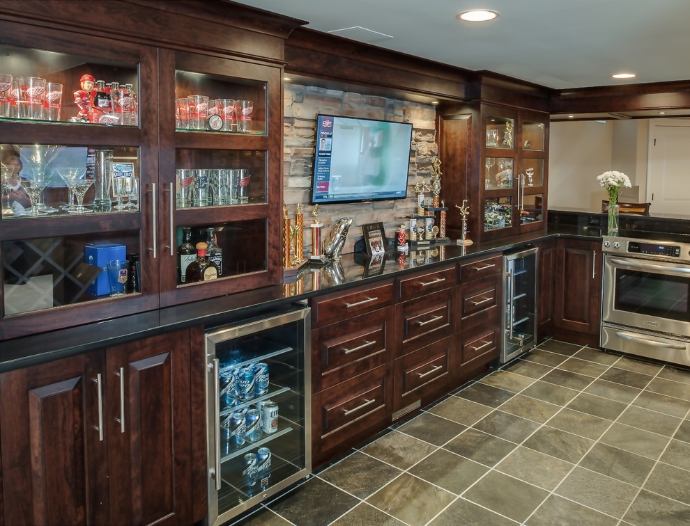 Photo of a large classic galley breakfast bar in Detroit with a submerged sink, raised-panel cabinets, dark wood cabinets, granite worktops, beige splashback, stone tiled splashback and slate flooring.