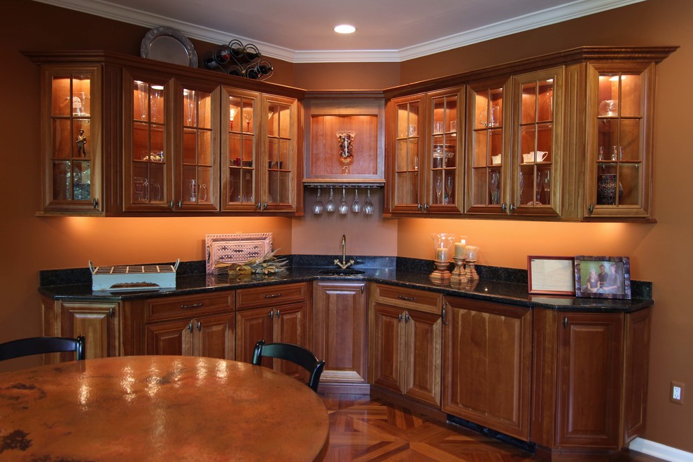 Example of a classic home bar design in Detroit with raised-panel cabinets, granite countertops, beige backsplash, ceramic backsplash and medium tone wood cabinets