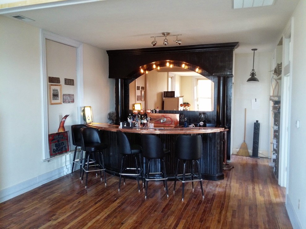 Große Stilmix Hausbar in U-Form mit Bartresen, schwarzen Schränken, Laminat-Arbeitsplatte, Küchenrückwand in Schwarz und hellem Holzboden in Indianapolis
