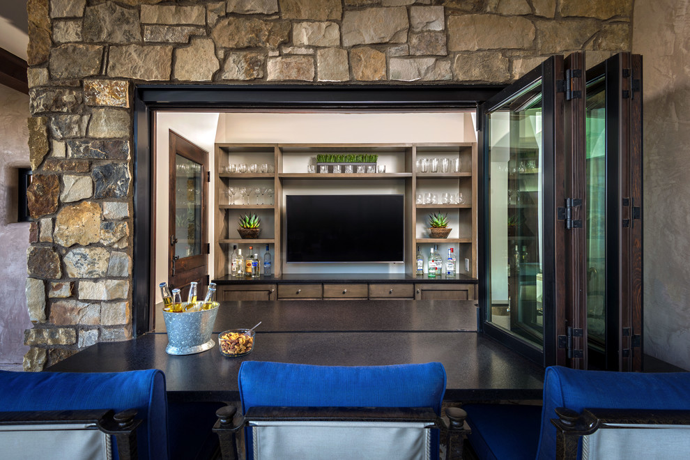 Immagine di un grande bancone bar mediterraneo con lavello sottopiano, ante in stile shaker, ante in legno bruno, top in granito e pavimento in pietra calcarea