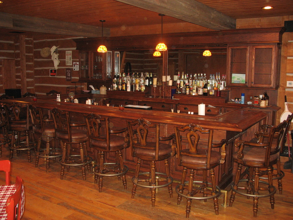 Diseño de bar en casa con barra de bar en U rural con armarios con paneles con relieve, puertas de armario de madera oscura, encimera de madera y suelo de madera en tonos medios