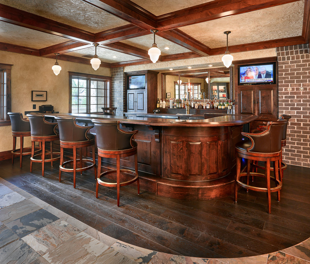 На фото: угловой домашний бар в классическом стиле с темными деревянными фасадами, деревянной столешницей и полом из сланца