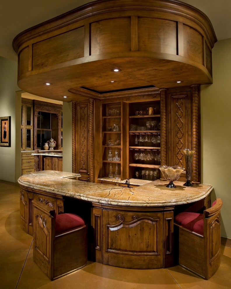 Modelo de bar en casa con barra de bar de galera tradicional con encimera de mármol, suelo de cemento, suelo marrón y puertas de armario de madera en tonos medios