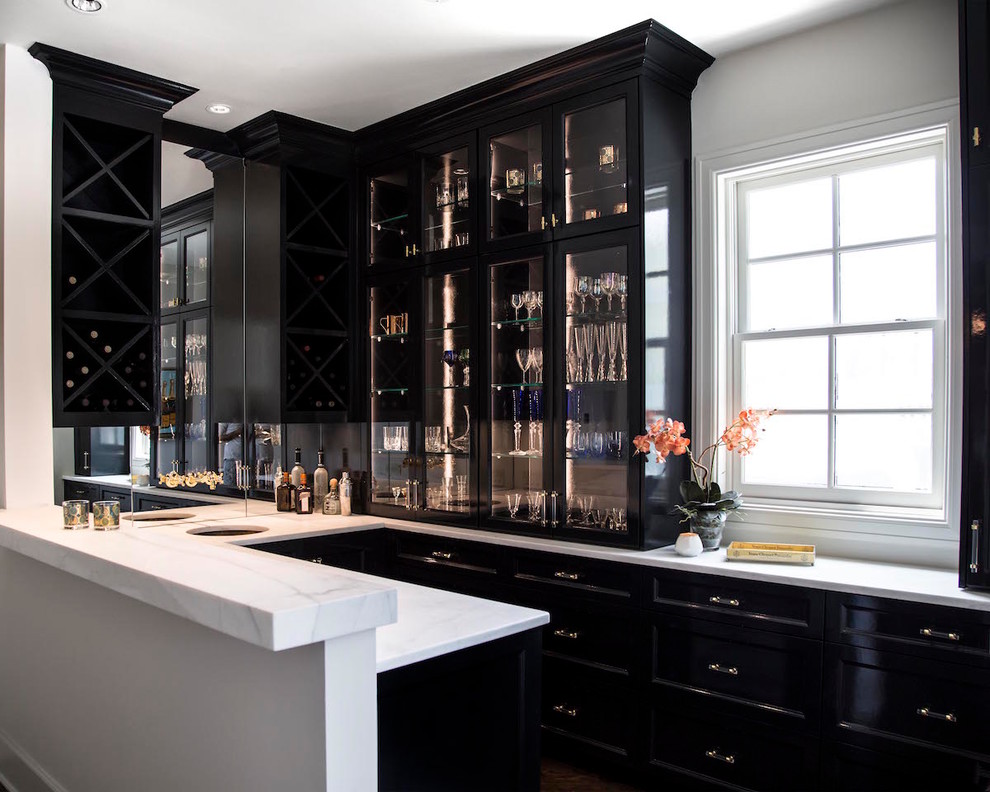 Large transitional u-shaped dark wood floor home bar photo in Austin with an undermount sink, recessed-panel cabinets, black cabinets, marble countertops and mirror backsplash