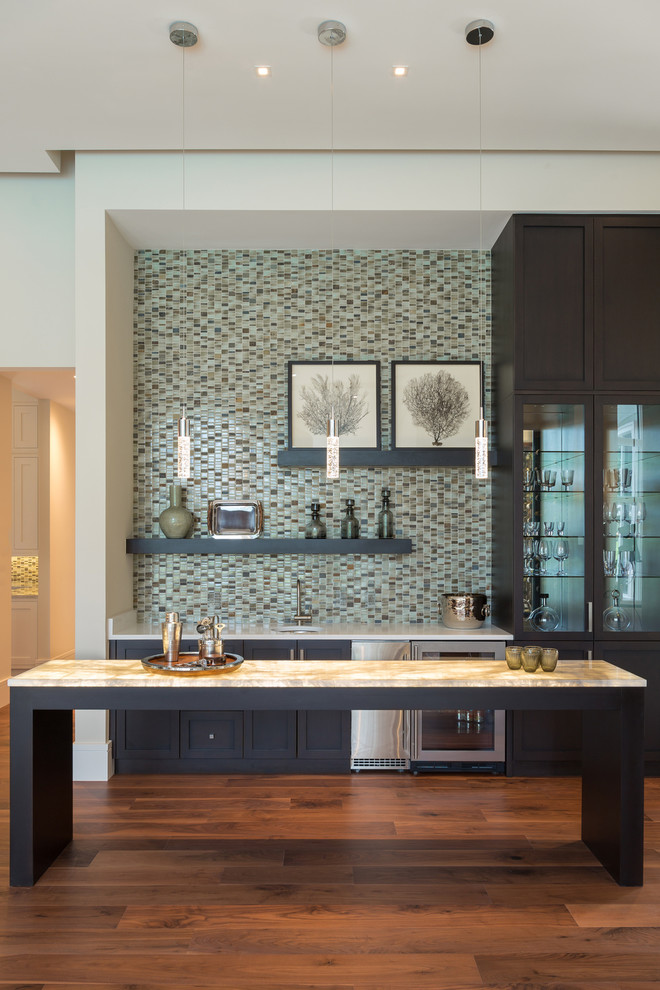 Inspiration for a large contemporary single-wall wet bar in Miami with a submerged sink, shaker cabinets, black cabinets, onyx worktops, multi-coloured splashback, mosaic tiled splashback, dark hardwood flooring and brown floors.