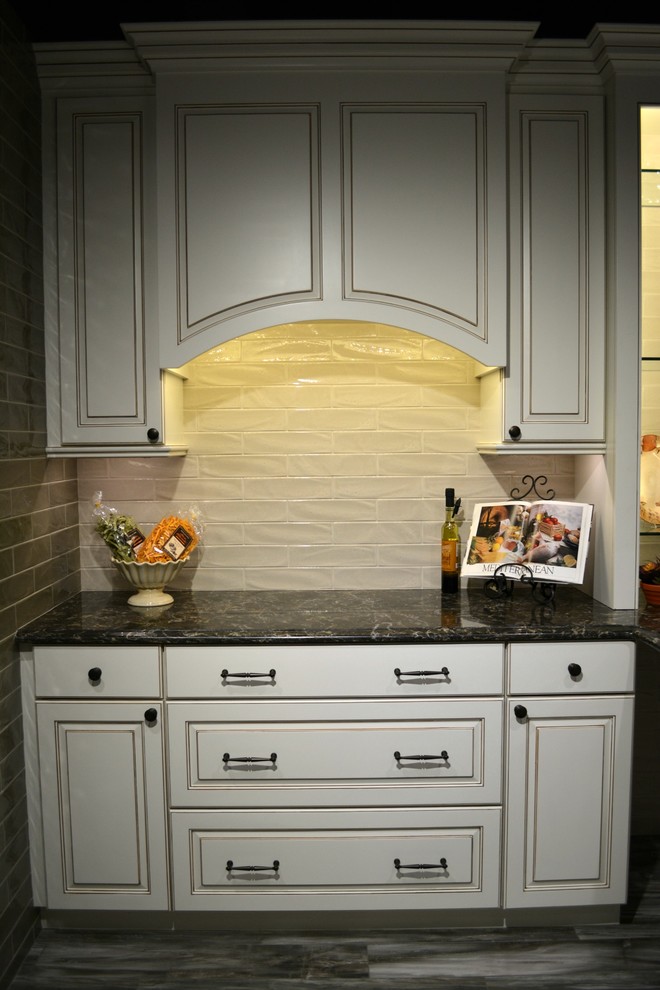 This is an example of a medium sized rustic single-wall wet bar in DC Metro with no sink, raised-panel cabinets, white cabinets, granite worktops, white splashback, metro tiled splashback and dark hardwood flooring.