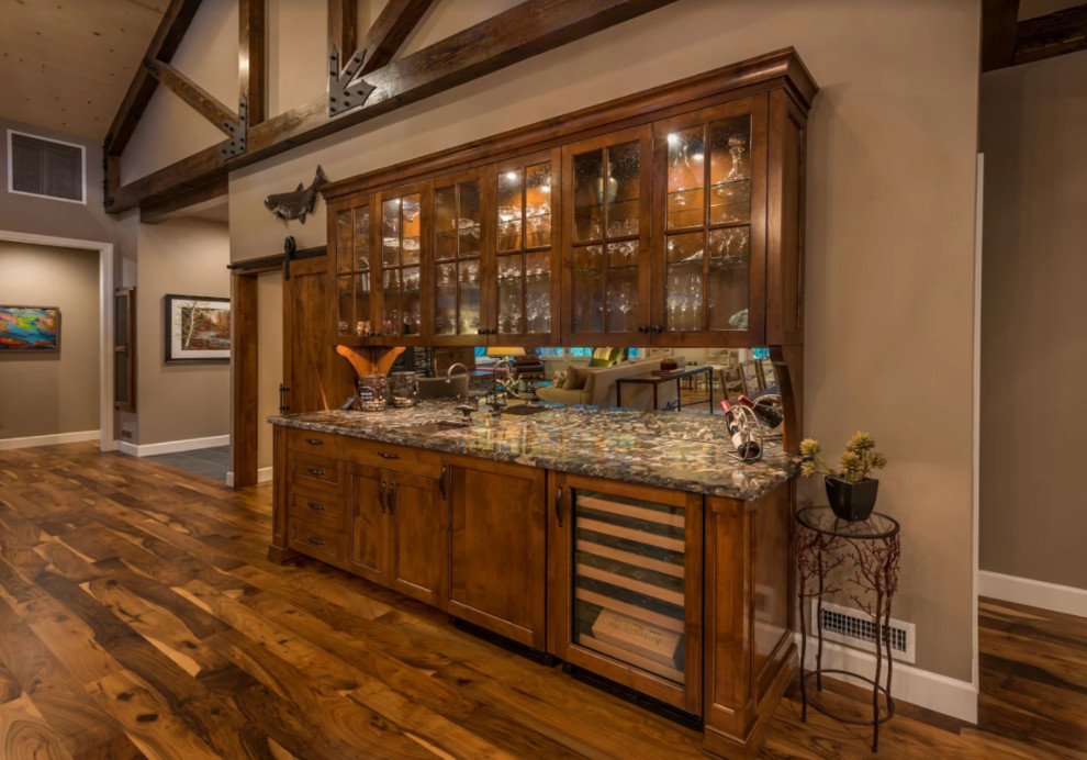 Design ideas for a medium sized rustic single-wall wet bar in Other with a submerged sink, recessed-panel cabinets, dark wood cabinets, granite worktops, mirror splashback, dark hardwood flooring and brown floors.