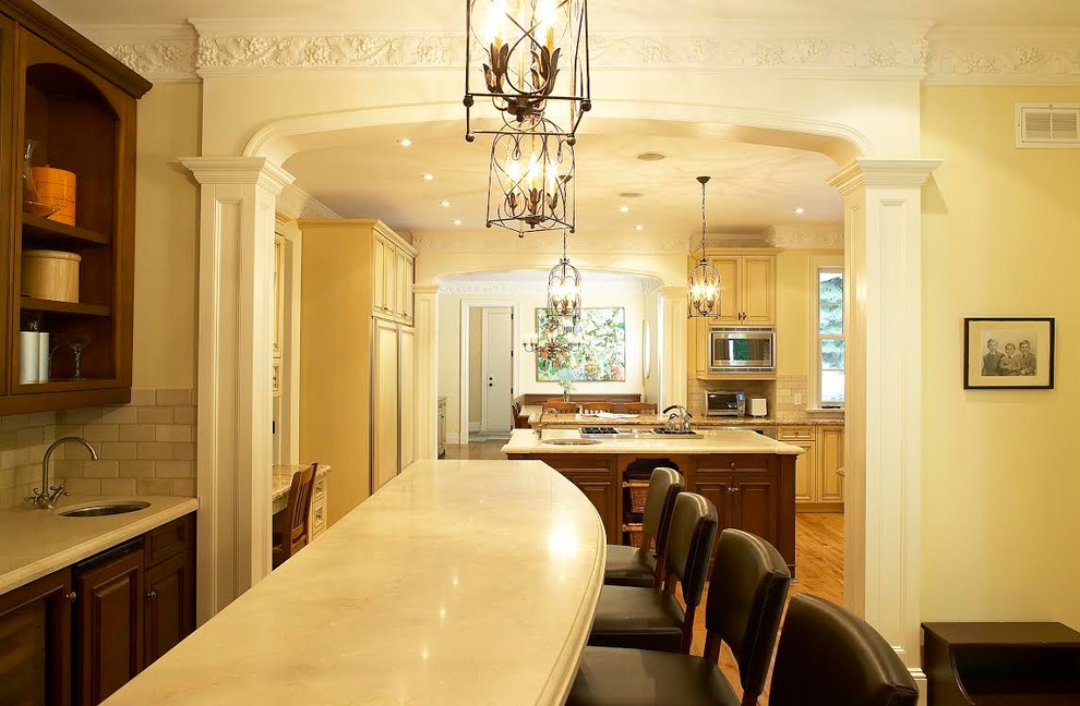 This is an example of a large traditional galley breakfast bar in Toronto with a submerged sink, raised-panel cabinets, dark wood cabinets, marble worktops, grey splashback, metro tiled splashback and medium hardwood flooring.