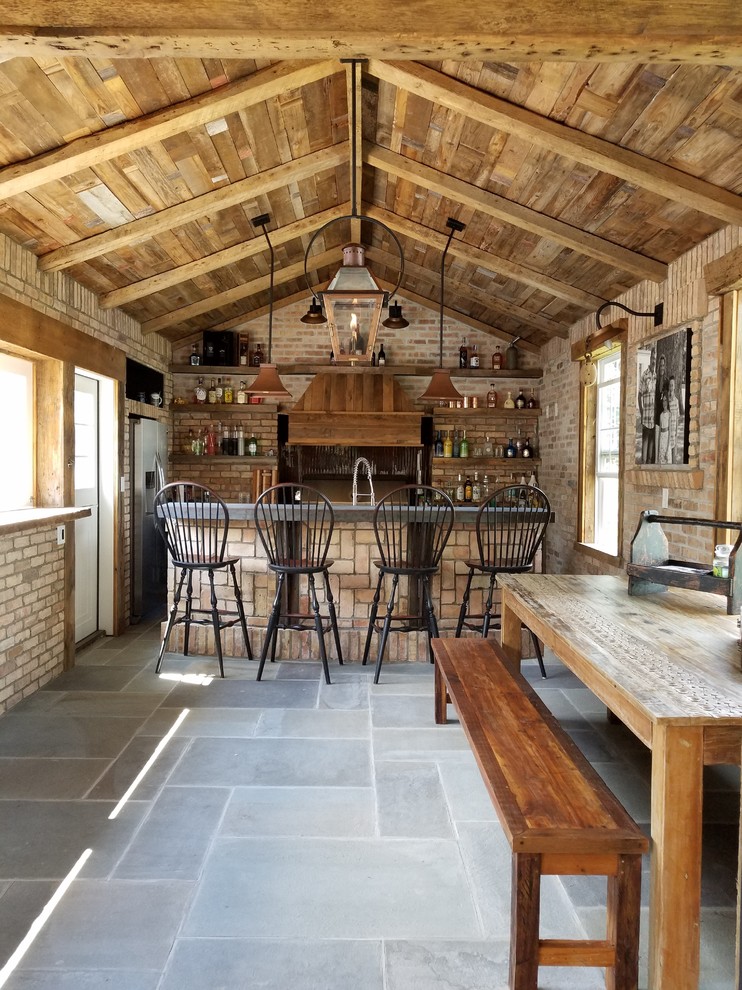 Cette image montre un bar de salon avec évier parallèle chalet en bois brun avec un placard sans porte, un plan de travail en béton, une crédence en brique, un sol en ardoise et un sol gris.