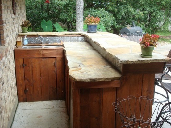 Inredning av en klassisk mellanstor l-formad hemmabar med vask, med skåp i mellenmörkt trä, en undermonterad diskho och betonggolv