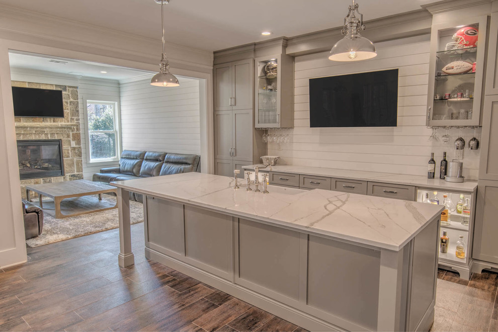 Inspiration for a mid-sized cottage porcelain tile and brown floor seated home bar remodel in Atlanta with shaker cabinets, gray cabinets, solid surface countertops, white backsplash, wood backsplash and white countertops