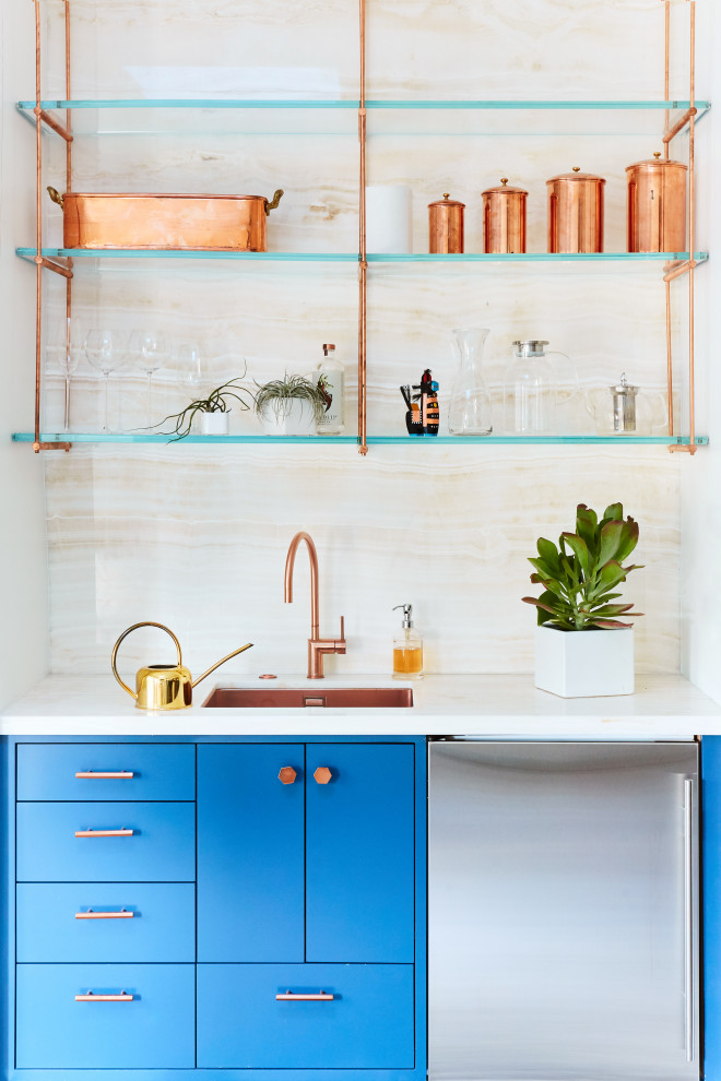 Inredning av en modern liten beige linjär beige hemmabar med vask, med en undermonterad diskho, släta luckor, blå skåp, beige stänkskydd, bänkskiva i onyx och stänkskydd i sten