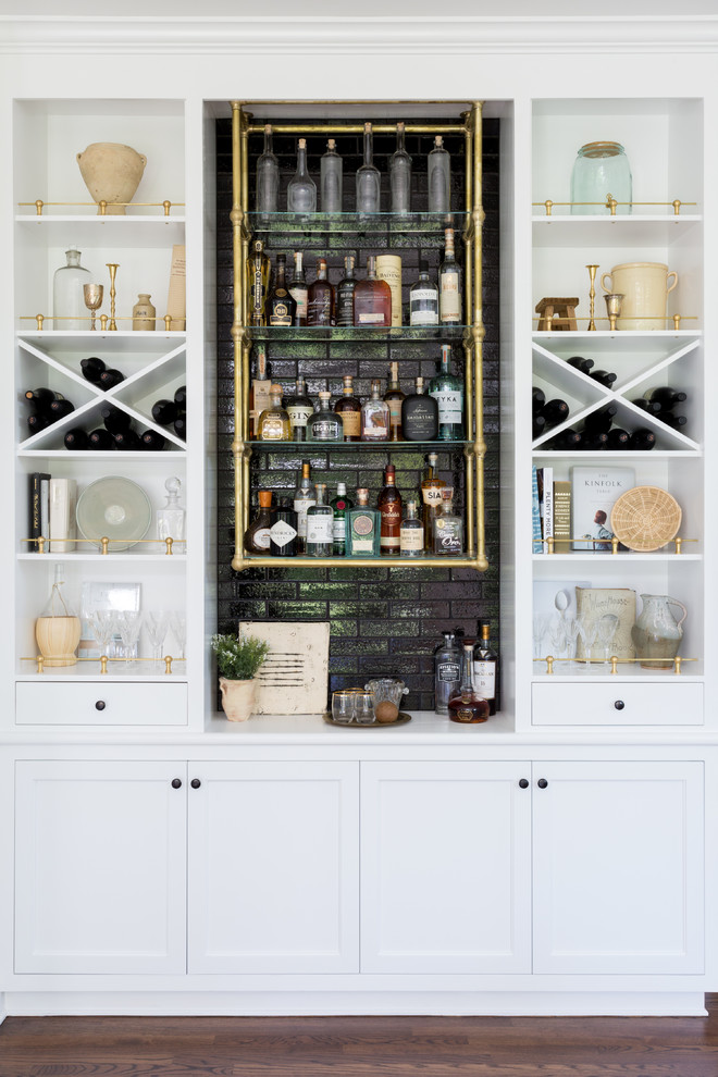 Example of a beach style single-wall dark wood floor and brown floor home bar design in Los Angeles with no sink, open cabinets, white cabinets, black backsplash and white countertops